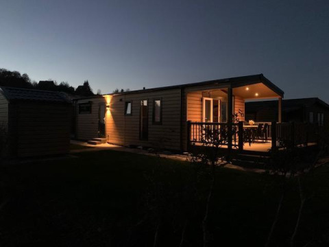 El Chalet Bergrose iluminado en Camping & Ferienpark Brilon en Alemania, fotografiado al anochecer.