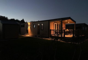 El Chalet Bergrose iluminado en Camping & Ferienpark Brilon en Alemania, fotografiado al anochecer.