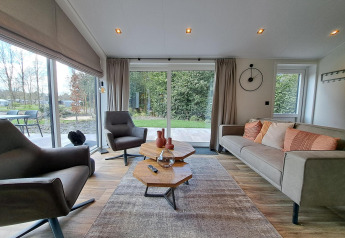 Modern living room at Hackfort 4 lodge in De Utrechtse Heuvelrug, Netherlands, with sleek furniture and large windows.