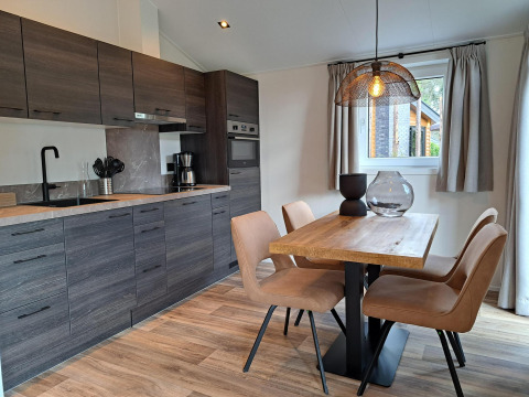 Cocina y comedor modernos en la cabaña Hackfort 4 en De Utrechtse Heuvelrug, con mesa y cuatro sillas de madera.
