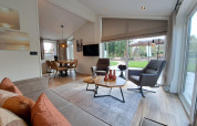 Modern lounge area of Hackfort 4 lodge with large windows and garden view, De Utrechtse Heuvelrug, Netherlands.