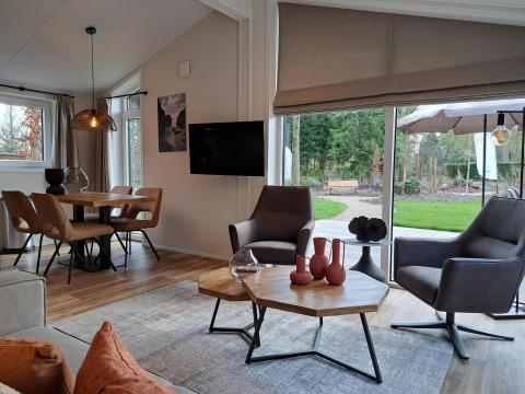 Interior moderno de la cabaña Hackfort 4 en De Utrechtse Heuvelrug, Países Bajos, con grandes ventanales y jardín.