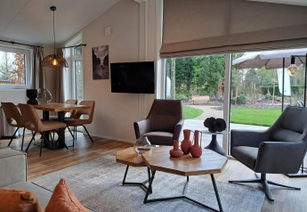 Intérieur moderne de la lodge Hackfort 4 à De Utrechtse Heuvelrug, Pays-Bas, avec grandes fenêtres et vue sur jardin.