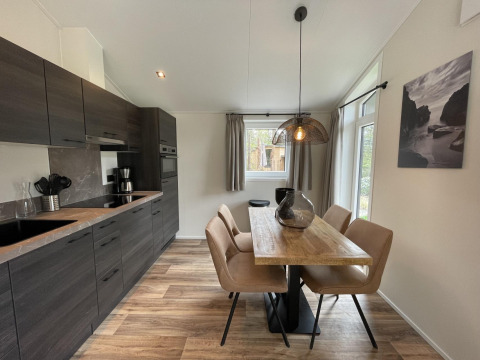 Modern kitchen and dining area in Hackfort 4 lodge at De Utrechtse Heuvelrug, Netherlands, with wooden table.