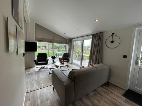 Sala moderna de la cabaña Hackfort 4 en De Utrechtse Heuvelrug, Países Bajos, con ventanas grandes y decoración elegante.