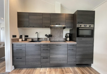 Cucina moderna grigia con elettrodomestici integrati e pavimento in legno al Hackfort 4, De Utrechtse Heuvelrug, Paesi Bassi.
