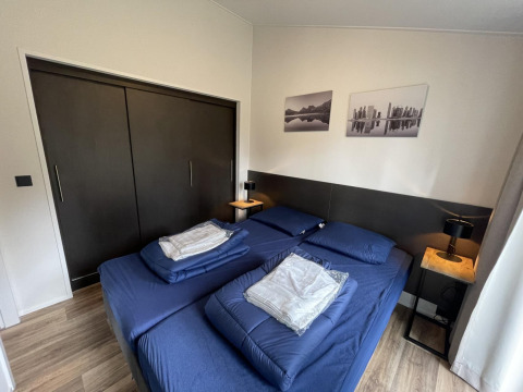 Modern bedroom at Hackfort 4 lodge, De Utrechtse Heuvelrug, Netherlands, with blue bedding and closets.