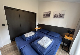 Modern bedroom at Hackfort 4 lodge, De Utrechtse Heuvelrug, Netherlands, with blue bedding and closets.