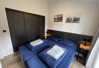 Camera moderna presso Hackfort 4, De Utrechtse Heuvelrug, Paesi Bassi, con biancheria da letto blu e armadi.