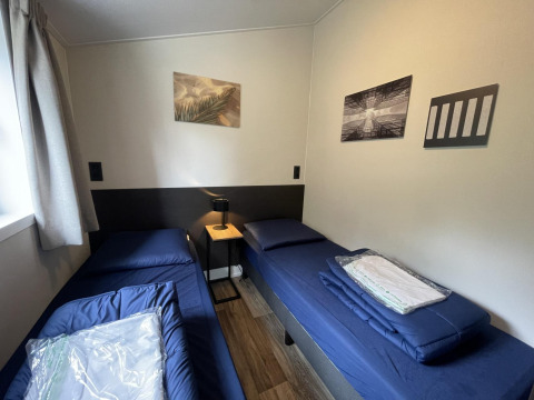Room at Hackfort 4 lodge in De Utrechtse Heuvelrug, Netherlands, with two single beds and wall art.
