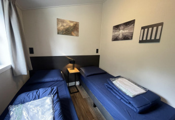 Room at Hackfort 4 lodge in De Utrechtse Heuvelrug, Netherlands, with two single beds and wall art.