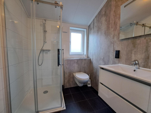 Baño moderno con ducha acristalada, inodoro suspendido y lavabo blanco en Hackfort 4, De Utrechtse Heuvelrug, Países Bajos.