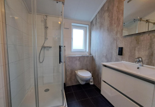 Baño moderno con ducha acristalada, inodoro suspendido y lavabo blanco en Hackfort 4, De Utrechtse Heuvelrug, Países Bajos.