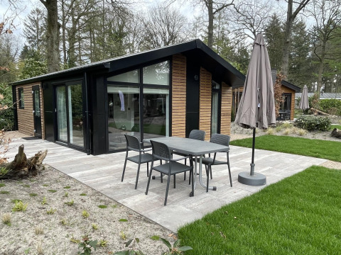 Moderne lodge Hackfort 4 aan De Utrechtse Heuvelrug in Nederland met terras, tuin en tuinmeubilair.