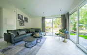 Salon moderne du lodge Hackfort MIVA avec de grandes baies vitrées sur De Utrechtse Heuvelrug, Pays-Bas.