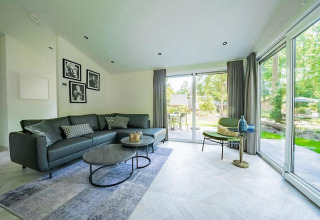 Modernes Wohnzimmer in der Hackfort MIVA-Lodge mit großen Fenstern und Blick auf De Utrechtse Heuvelrug, Niederlande.