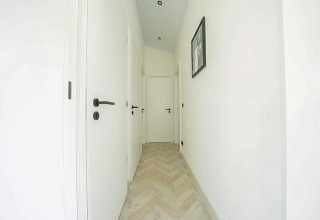 Couloir lumineux aux portes blanches et parquet clair à Hackfort MIVA, De Utrechtse Heuvelrug, Pays-Bas.
