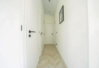 Bright hallway with white doors and light herringbone flooring at Hackfort MIVA, De Utrechtse Heuvelrug.