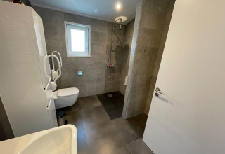 Salle de bain accessible avec douche, toilettes et barres d'appui au Hackfort MIVA, De Utrechtse Heuvelrug, Pays-Bas.