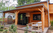 Petite maison en bois avec terrasse couverte, fauteuil suspendu et salon de jardin à Beekbergen, Pays-Bas.