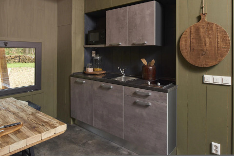 Moderne lille hus køkken med grå skabe, træbord og stort træskærebræt i Tiny House 4 Hottub, Beekbergen.