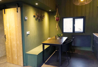 Foto degli interni di una tiny house moderna con porta in legno, pareti verdi e zona pranzo a Beekbergen.
