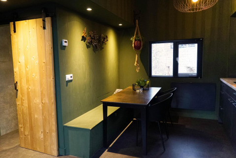 Interieurfoto van een moderne tiny house met houten schuifdeur, groene muren en eethoek in Beekbergen.