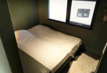 Camera da letto con letto matrimoniale e finestra nella Tiny House 4 Hottub a Beekbergen, Paesi Bassi.