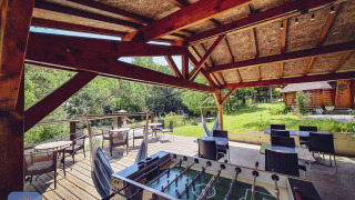 Terraza cubierta con futbolín, sillas colgantes y mesas en Camping Des Randonneurs, en Occitania, Francia.