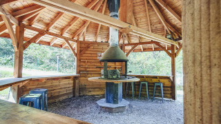 Pabellón de madera con chimenea y asientos en Camping Des Randonneurs, Occitania, Francia.