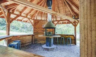 Pavillon en bois avec cheminée et sièges au Camping Des Randonneurs en Occitanie, France.
