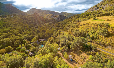 Vista aerea del paesaggio montuoso e verdeggiante vicino a Fenouillet, Occitania, Francia, con cabine tra gli alberi.