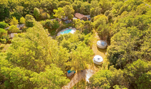 Aerial view of Camping Des Randonneurs holiday park in Occitanie, France, showing pool, cabins and trees.