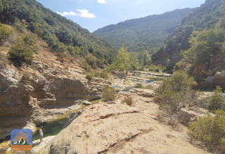 Panorama di una vallata rocciosa e colline verdi al Camping Des Randonneurs in Occitania, Francia.