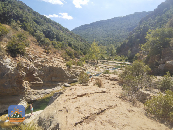 Panorama di una vallata rocciosa e colline verdi al Camping Des Randonneurs in Occitania, Francia.