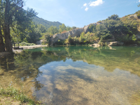 Paisaje en Camping Des Randonneurs, Occitanie, Francia, con agua cristalina y vegetación verde alrededor.