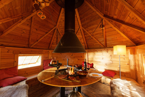 Acogedora cabaña de madera en Camping Des Randonneurs, Occitania, Francia, con chimenea y zona de comedor.