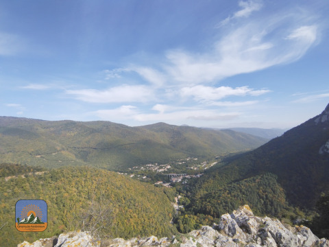 Panoramic view of lush green hills and valley near Fenouillet, Occitanie, France, with blue sky above.