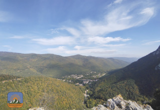 Panoramic view of lush green hills and valley near Fenouillet, Occitanie, France, with blue sky above.