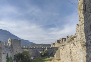 Blick auf mittelalterliche Festungsmauern bei Fenouillet, Okzitanien, Frankreich, mit Bergen im Hintergrund.