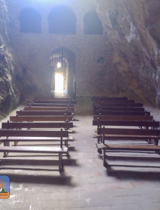 Bancos de piedra en una capilla cueva cerca de Fenouillet, Occitania, Francia, con luz entrando.