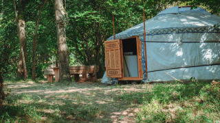 Una yurta tradizionale con porte in legno intagliato nella foresta, Camping Des Randonneurs, Francia, senza servizi.