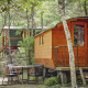 To hyggelige Gipsy-vogne i en skov, med et bord og fire stole udenfor, perfekt til naturcamping.