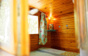 Interno della cabina Gipsy wagon con pareti in legno, tenda colorata e finestra, senza bagno privato.