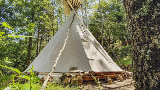 Et Wigwam-telt uden private sanitære faciliteter i en frodig skov på Camping des Randonneurs.