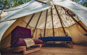 Interno di una tenda Wigwam con pavimento in legno, letto e divano al Camping Des Randonneurs, Francia.
