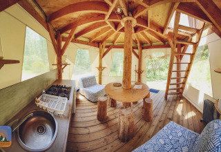 Interior de una tienda burbuja tipi con muebles rústicos en Camping Des Randonneurs, Francia, rodeado de naturaleza.