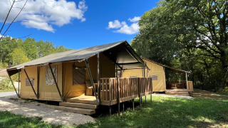 Tienda safari Lodgetent con instalaciones sanitarias y terraza de madera en Camping Lac aux Oiseaux, Francia.