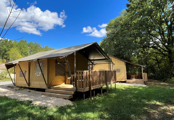 Tienda safari Lodgetent con instalaciones sanitarias y terraza de madera en Camping Lac aux Oiseaux, Francia.
