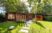 Træchalet og have med udendørs spiseplads i solskin ved Bungalowpark Het Verscholen Dorp, Holland.